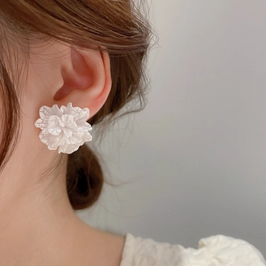 Close-up of minimalist white acrylic flower earrings with pleated texture on model