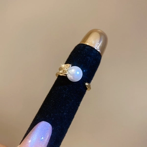 Detailed view of large white pearl on golden leaf adjustable ring with black display