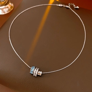Close-up of cylindrical silver necklace pendant with blue and white zircon stones