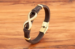 Close-up of brown braided leather bracelet with golden infinity charm on wood background