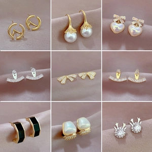 Collection of gold-plated geometric earrings with pearls, rhinestones, and silk background