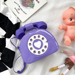 Detail of purple retro telephone crossbody bag with glossy finish and dial design