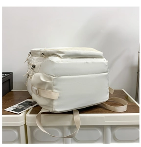 Close-up of white nylon backpack side with adjustable buckles and zipper pockets