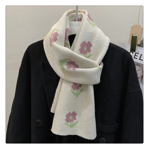 Detail view of cream knitted scarf with purple floral pattern on black coat neck