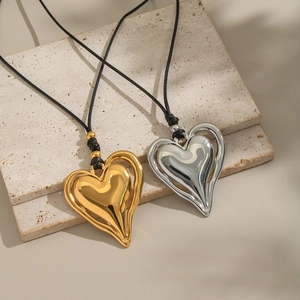Pendentifs cœur 3D classiques en or et argent avec cordon noir sur fond texturé