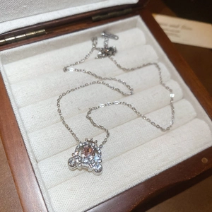 Macro detail of pumpkin carriage necklace with pink heart crystal in a gift box
