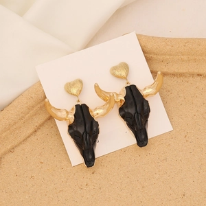 Detailed close-up of Bohemian bull skull earrings with gold heart studs on display card