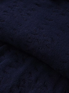 Close-up of deep blue knitted fabric texture showing intricate weave and premium fiber detail
