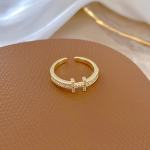 Close-up of adjustable gold H-shaped ring with pavé zircons on brown leather texture