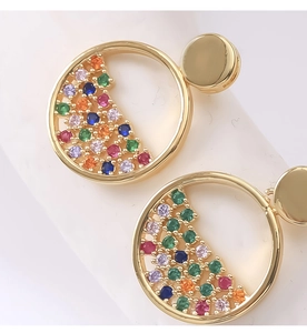 Dettaglio macro di orecchini tondi dorati con zirconi multicolori con micro-incastonatura