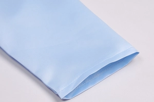 Detail shot of smooth sky blue silk fabric with precise stitching and elegant satin luster