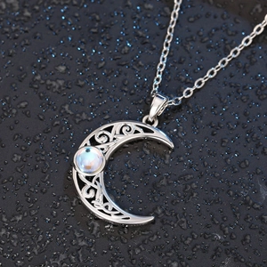 Close-up of crescent moon necklace with intricate filigree and blue moonstone