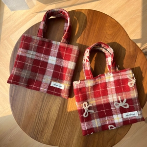 Sacs à main en laine à carreaux rouges avec nœud sur une table en bois ensoleillée