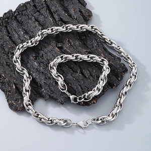 Polished silver stainless steel twist chain necklace and bracelet set on a dark textured wood