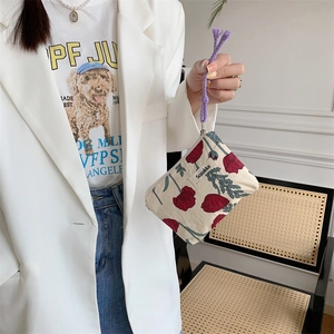 Floral canvas pouch with purple drawstring shown as a handheld fashion accessory