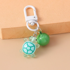 Detail of green resin turtle keychain with matching bell and polished metal ring
