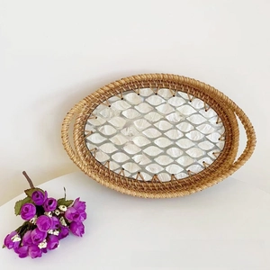 Detail of oval rattan tray with shell inlay bottom and dual handles for home storage