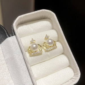 Detail of crown shaped earrings with white pearl and sparkling zircon in a jewelry box