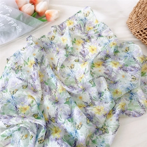 Detail view of lightweight square silk scarf with purple and yellow floral patterns