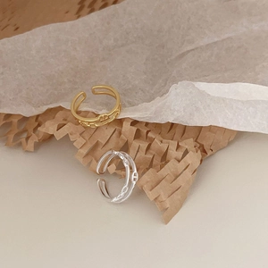 Detailed view of gold and silver anchor chain adjustable rings on textured paper
