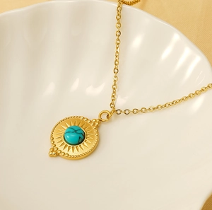 Detail of 18K gold-plated stainless steel star pendant with turquoise in a shell tray