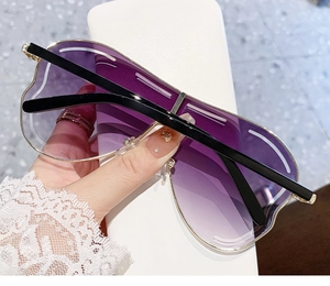 Détail de lunettes de soleil en forme de cœur avec verres violets dégradés et monture dorée
