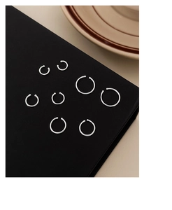 Multiple sizes of minimalist sterling silver hoops displayed on a black geometric stand