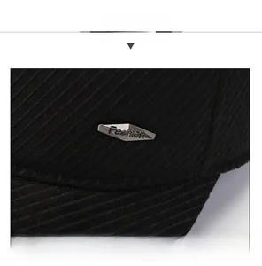 Macro shot of black corduroy fabric texture and silver 'Fashion' metal emblem on the cap