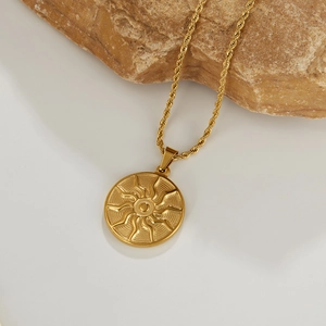 Detailed close-up of golden solar totem pendant with wave textures on a rope chain