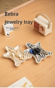 Star-shaped ceramic jewelry trays with zebra stripes and gold edges on wooden desk