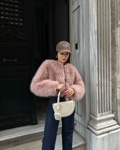 Giacca chic in ecopelliccia rosa abbinata a borsa bianca a mezzaluna e cappellino marrone