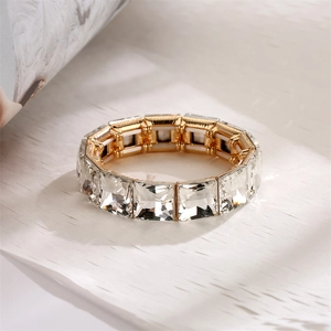Macro shot of geometric square-cut clear crystals on a wide elastic gold alloy bracelet