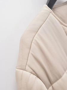 Macro shot of beige quilted jacket showing precise diamond stitching and fabric texture