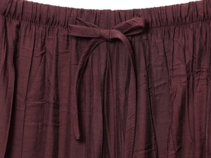 Detailed macro view of dark burgundy pleated fabric with elastic waist and drawstring cord