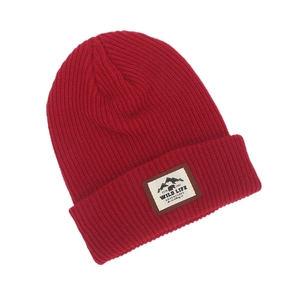 Detail of red knit beanie featuring a mountain wildlife patch and ribbed texture