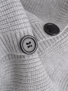 Close-up of gray knit cardigan featuring textured weave and black resin button details