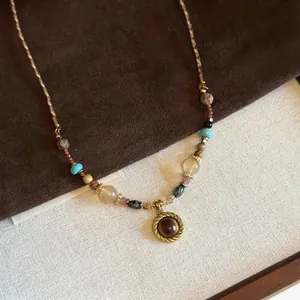 Detail of beaded necklace featuring tiger eye pendant and multi-color stones on woven cord