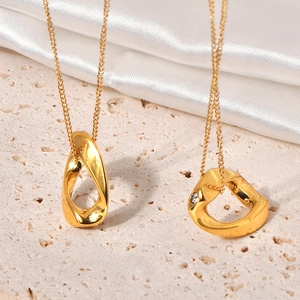 Détail du collier doré avec pendentif géométrique et zircon sur fond de pierre texturée