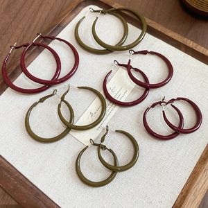 Close-up of geometric hoop earrings in olive green and burgundy drip oil finish
