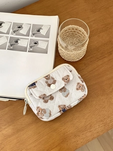 Detailed view of white quilted mini bag with cute bear print on a rustic wooden desk
