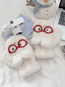Detail of plush white monster mittens with red glasses embroidery and furry texture
