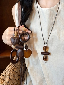 Close-up of geometric resin and wood pendants on long adjustable cord necklaces