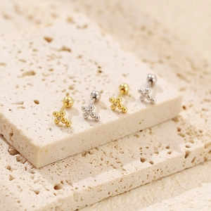 Detail of silver and gold cross stud earrings with sparkling crystals on stone base