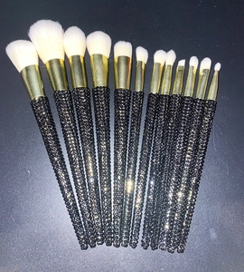 Detailed flat lay of 12 professional makeup brushes with black rhinestone handles and gold ferrule