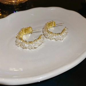 Close-up of C-shaped gold earrings with sparkling channel-set rectangular zircon stones