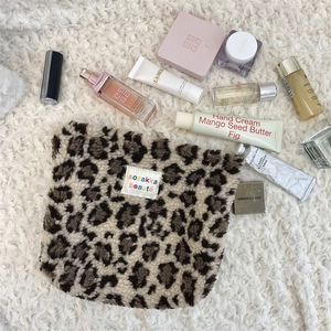 Close-up of leopard print plush cosmetic bag on a soft cream rug with luxury skincare items