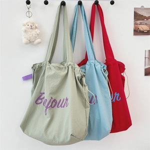 Three textured nylon bags in green, blue, and red with drawstring and sheep pendant