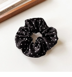 Detailed view of black polka dot satin scrunchie texture with elastic ruffled folds