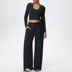 Détail d'un haut de yoga croisé noir et d'un pantalon de sport large à taille haute assorti