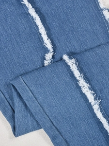 Vue détaillée des bords effilochés et de la texture denim sur le body bleu
